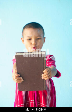 Little boy Holding in einem großen Buch auf einem hellblauen Hintergrund. Stockfoto