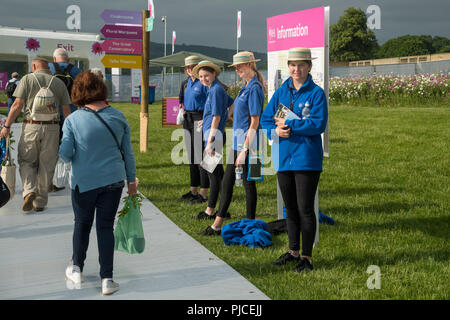 4 Junge weibliche Führer oder welcomers stand by Information Board&Smile herzlich als Besucher von RHS Chatsworth Flower Show, Derbyshire, England, UK zu Fuß Stockfoto