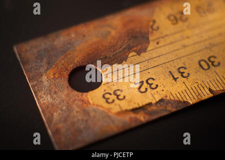 Altes rostiges Metall Lineal mit numerierten Etiketts Risse auf schwarzem Hintergrund Oberfläche mit kostenlose Kopie Raum Stockfoto