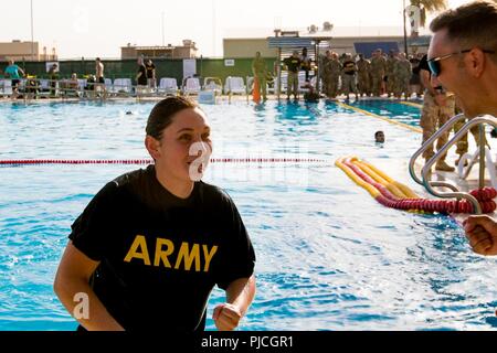 CAMP ARIFJAN, Kuwait - eine stolze 28 ID "Eiserne Division" Soldat, SPC. Erin Murphy, erfolgreich, Schwamm 100 Meter in Dienstuniform in weniger als vier Minuten und war in der Lage, ihre Pflicht Uniform im tiefen Wasser, das über Ihre körperlichen Training T-Shirt und Shorts getragen wurde, um sie zu entfernen. Staff Sgt. Lance Moser cheers nach Murphy durch die erste Veranstaltung der Bundeswehr Proficiency Abzeichen Qualifikation streichelte. Stockfoto