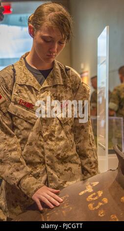 Anna Elkins, Student aus Granbury High School in Granbury, Texas, berührt ein Stück des World Trade Center während der Marine Corps Recruiting Befehl Summer's Leadership 2018 und Charakter Development Academy am nationalen Museum der Marine Corps im Dreieck, Virginia, 21. Juli. Im Laufe der Woche, Studenten wurden herausgefordert, die außerhalb ihrer Komfortzonen zu Schritt und ihr Vertrauen und Führungsqualitäten stärken. Sie hörten von namhaften Führer, darunter Unternehmer, Überlebende des Holocaust und Marines aus allen Lebensbereichen. Die körperliche Fitness wurde auch durch physische betonte Stockfoto