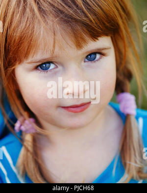 Closeup Portrait von cute adorable kleine Rothaarige kaukasische Mädchen mit blauen Augen in die Kamera. Glückliche Kindheit Konzept Stockfoto