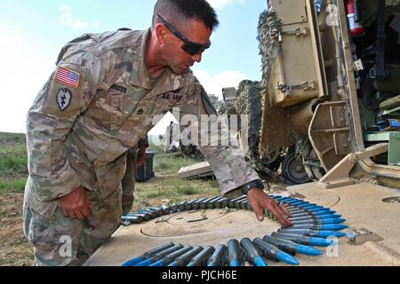 Armee Sgt. 1. Klasse Warren Johnson, ein platoon Sergeant zu Alpha Company zugewiesen., 2nd Battalion, 5th Cavalry Regiment, 1st Armored Brigade Combat Team, 1.Kavallerie Division, inspiziert 25 mm hoch explosiven Runden während einer schießwesen bei Novo Selo, Bulgarien, 19. Juli 2018. Die Runden sind für einen M242 Chain Gun, eine Waffe zu einem Bradley Fighting Fahrzeug angebracht. Stockfoto