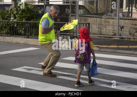 CHATAN STADT, Okinawa, Japan - Oberst Vincent Ciuccoli interagiert mit einem Kind während freiwillig als Crossing Guard für Kitatama Volksschule Juli 19 in Chatan Stadt, Okinawa, Japan. Ciuccoli freiwillig auf die Partnerschaft mit der lokalen Gemeinschaft aufzubauen und die Sicherheit der Kinder zu gewährleisten, wie sie entlang der geschäftigen Straßen von chatan Stadt zur Schule. Ciuccoli ist der Lagerkommandant von Camp Foster und der Zentrale und den kommandierenden Offizier der Unterstützung Bataillon, Marine Corps Installationen Pacific-Marine Corps Base Camp Butler, Japan. Stockfoto