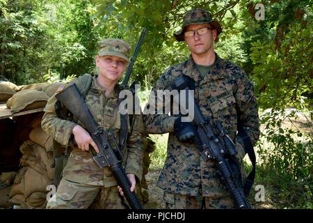 In diesem Bild, das von der US-Armee, Armee Sgt freigegeben. Jessica Robbins, 2061St Multi Role Bridge Company, Kentucky Army National Guard, Lance Cpl. Dustin Wheatley, 6. Unterstützung der Techniker Bataillon, US Marine Corps Kräfte finden, geben Ihnen Sicherheit von Ihrem improvisierten foxhole für die 489Th Engineer Battalion, 420Th Engineer Brigade, U.S. Army Reserve, Juli 21, 2018, während der Fluss Angriff 2018 am Fort Chaffee in Fort Smith, Arkansas. Die Übung ist eine gemeinsame Operation vereint Elemente aus der Armee, Army National Guard, der regulären Armee und das US Marine Corps für Motor Stockfoto