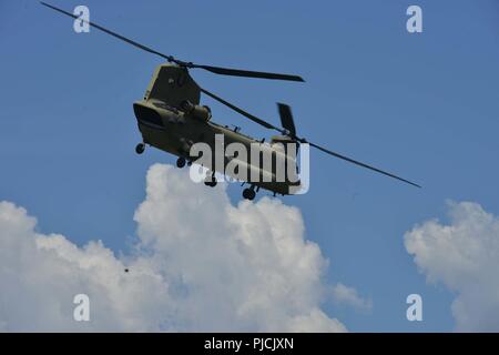 Ein 12 Combat Aviation Brigade CH-47 Chinook Hubschrauber fliegt durch den klaren Himmel der Juliet Drop Zone während eines multinationalen Betrieb in Pordenone Aviano, Italien, 19. Juli 2018. Die kombinierte Übung demonstriert den multinationalen Kapazitäten der zerstreuten Gemeinschaft und auf die Erhöhung der NATO operativer Standards und der Entwicklung von individuellen technischen Fertigkeiten konzentriert Stockfoto