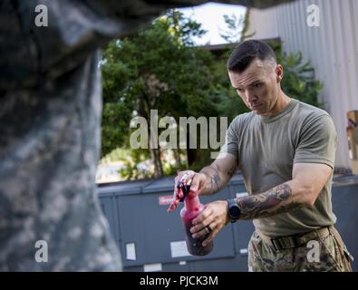 U.S. Army Staff Sgt. Chase Johnson, U.S. Army Medical Aktivität operations NCO, gilt moulage zu einem Freiwilligen vor einem Flugzeugabsturz Übung in Joint Base Langley-Eustis, Virginia, 17. Juli 2018. Moulage geholfen, die Übung durch ein realistischeres Szenario für das Personal reagiert auf den Vorfall zu verbessern. Stockfoto