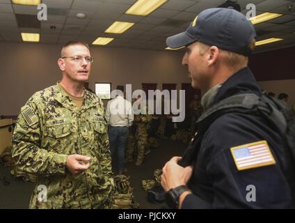 SAN DIEGO (24. Juli 2018) U.S. Navy hinten Adm. Dave Welch, Commander, kombinierte Task Force (CTF) 177 und Naval Oberfläche und Mine Warfighting Development Center (SMWDC), Links, spricht mit der U.S. Coast Guard (USCG) Petty Officer 1st Class Devon Waite, USCG Canine Explosive Detection Team während eines geplanten Besuch in der U.S. Coast Guard Sektor San Diego als Teil der Felge des Pazifiks (Rimpac) Übung im südlichen Kalifornien Bereich von Operationen, Juli 24. 25 Nationen, 46 Schiffe, 5 U-Boote, über 200 Flugzeuge und 25.000 Angestellte beteiligen sich an Rimpac vom 27. Juni bis 2. August Stockfoto