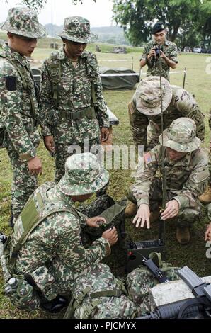 Soldaten mit dem 15 Royal Malay Regiment, zeigen ihre Radio zu US-Armee Soldaten mit Charlie Company, 100-Bataillon, 442Nd Infanterie Regiment, US Army Reserve, während der Übung Keris Streik, Juli 24, 2018, Camp Senawang, Malaysia. Malaysischen Soldaten beweisen ihre Dschungel Taktiken zur Vorbereitung der Keris Streik jungle Bereich Training. Stockfoto