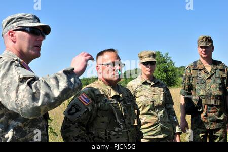 Us-Armee Sgt. 1. Klasse John Barnes (Mitte), ein Beobachter/coach Trainer der Joint Multinational Readiness Center Falcon's Team zugewiesen, hilft bei der Deutschen Bundeswehr Reservisten mit Erste-hilfe-Verfahren Vor medizinische Luft evakuierungsübung an JMRC von Hohenfels, Hohenfels, Deutschland, 19. Juli 2018. Eine nasale pharyngealen Atemwege gerät, die hilft, die Atemwege, ist im nasalen Barnes' Hohlraum gelegt die Leichtigkeit, in der sie eingefügt werden können zu demonstrieren. Nebraska und Kansas Army National Guard Soldaten beteiligen sich an multinationalen Interoperabilität Ausbildung, die e Stockfoto