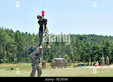 Ein Soldat der US-Armee auf das erste Bataillon zugeordnet, 376 Aviation Regiment, Nebraska Army National Guard, hilft bei der Deutschen Bundeswehr Reservisten mit medizinische Luft Evakuierungsübung in Hohenfels training Bereich der Gemeinsamen Multinationalen die Bereitschaft, Hohenfels, Deutschland, Juli 19, 2018 Zug. Nebraska und Kansas Army National Guard Soldaten beteiligen sich an multinationalen Interoperabilität Ausbildung, mit der die Beziehung zwischen den USA und dem Gastgeberland verbessert. Stockfoto