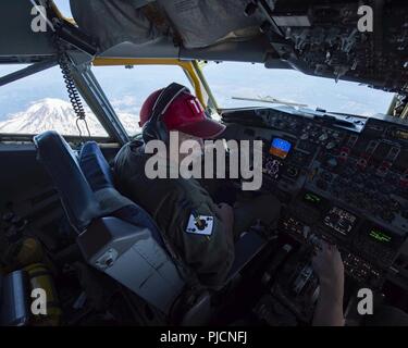 Kapitän Jon Cael, ein Pilot aus dem 141 Luftbetankung Flügel, Chats mit dem co-pilot als der Tanker vorbei Mt. Rainier während der Luft- und Raumfahrt-Alert CrossTell training Juli 24, 2018. Der Tanker flog nach westlichen Oregon zu F-16 Fighting Falcons unterstützen und F-15 Adler die Teilnahme an der Übung. CrossTell ist eine dreitägige Übung mit mehreren Air National Guard Einheiten, die Civil Air Patrol, und der U.S. Coast Guard Dreh-wing Luft abfangen Einheiten Ausbildung zu leiten, in der Luft fängt sicher escort Übertreter aus eingeschränkten Luftraum zu replizieren. Stockfoto