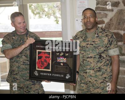 Major Derek Schmirgel, base Adjutant, präsentiert ausgehende MCLB Barstow kommandierender Offizier Oberst Sekou Karega eine Plakette, die von den Offizieren des MCLB während einer Hagel und Abschied ehrt sowohl ausgehende und eingehende Kommandanten, 18. Juli an der Generalmajor James L. Tag Konferenzzentrum an Bord MCLB Barstow. Stockfoto