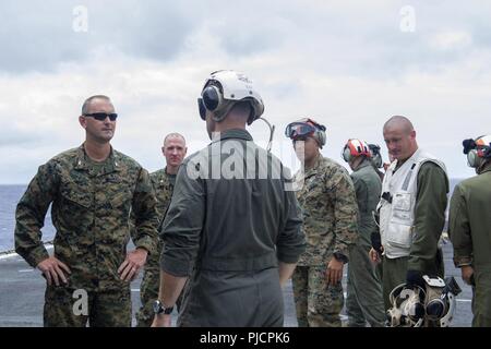 Freigegeben PAZIFISCHER OZEAN (16 Juli 2018) - Marine Corps. Colonel Chandler S. Nelms, Links, kommandierender Offizier der 13 Marine Expeditionary Unit (MEU), spricht mit Segler auf dem Flugdeck der Wasp-Klasse amphibisches Schiff USS Essex (LL 2), die während einer planmäßigen Einsatz von Essex Amphibious Ready Group (ARG) und 13th Marine Expeditionary Unit (MEU). Das Essex ARG/MEU Team ist ein stark, flexibel, reaktionsschnell und gleichbleibende Kraft in der Lage, Manöver Kriegsführung in allen Domänen; es ist ausgestattet und skalierbar auf jede Krise von der humanitären Hilfe und Katastrophenhilfe zu conting zu reagieren Stockfoto