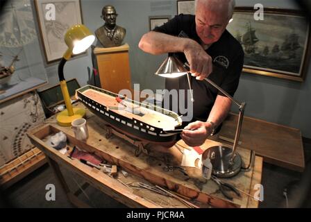 Pat Roll, eine freiwillige Modell Werft, arbeitet auf einem Schiff Modell der USS Constitution in der Galerie der Hampton Roads Naval Museum. Pat zog sich von der US-Marine, und Freiwilligen wöchentlich im Museum. Die Hampton Roads Naval Museum ist eines von zehn Marine Museen, die von der Marine Geschichte & Kulturerbe Befehl betrieben werden. Es feiert die lange Geschichte der US Navy in der Region Hampton Roads von Virginia und ist in Zusammenarbeit mit Nauticus in der Innenstadt von Norfolk, Virginia gelegen. Stockfoto