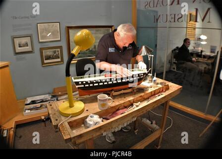 Pat Roll, eine freiwillige Modell Werft, arbeitet auf einem Schiff Modell der USS Constitution in der Galerie der Hampton Roads Naval Museum. Pat zog sich von der US-Marine, und Freiwilligen wöchentlich im Museum. Die Hampton Roads Naval Museum ist eines von zehn Marine Museen, die von der Marine Geschichte & Kulturerbe Befehl betrieben werden. Es feiert die lange Geschichte der US Navy in der Region Hampton Roads von Virginia und ist in Zusammenarbeit mit Nauticus in der Innenstadt von Norfolk, Virginia gelegen. Stockfoto