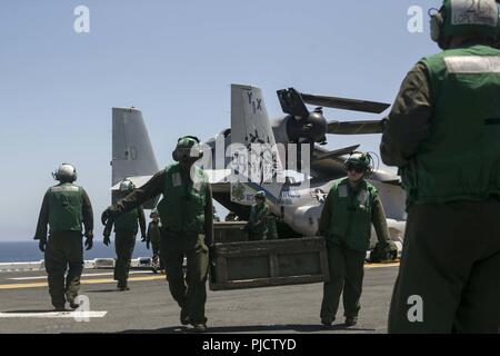 Pazifik - US-Marines mit Marine Medium Tiltrotor Squadron 166 verstärkt, 13 Marine Expeditionary Unit (MEU), Off-load Gang aus einer MV-22 Osprey B an Bord der Wasp-Klasse amphibisches Schiff USS Essex (LL 2), die während einer planmäßigen Einsatz der Essex Amphibious Ready Group (ARG) und die 13. MEU, 11. Juli 2018. Das Essex ARG/MEU Team ist eine starke, flexiblen, reaktionsschnellen und gleichbleibende Kraft in der Lage, Manöver Kriegsführung in allen Domänen; es ist ausgestattet und skalierbar auf jede Krise von der humanitären Hilfe und Katastrophenhilfe zu Blindbewerbungen zu reagieren. Stockfoto