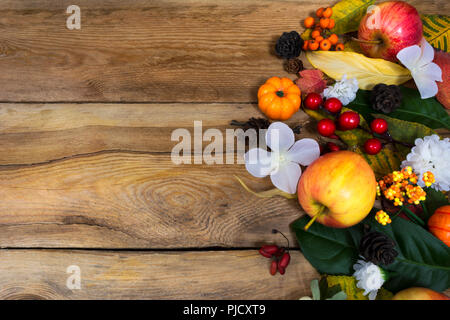 Thanksgiving oder fallen Gruß Hintergrund mit rand von äpfeln, Beeren, Blättern und weissen Blüten auf dem rustikalen Holztisch, kopieren Raum Stockfoto