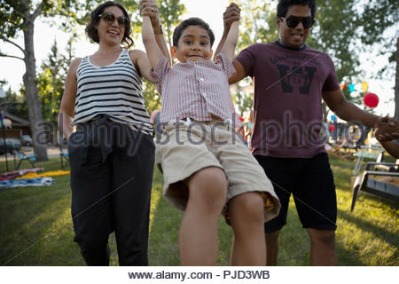 Verspielte Eltern schwingen boy in park