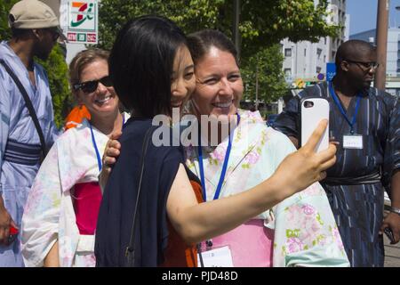 YOKOSUKA, Japan (17. Juli 2018) - Eri Ishida und Jen Pollard posieren für ein Foto bei einer Community Relations Veranstaltung der US-Flotte Aktivitäten (FLEACT) Yokosuka und Yokosuka city gehostet werden. Yokosuka, Matrosen und Familie Mitglieder trugen Yukata, einer ungezwungenen japanischen Sommer Kleid, besuchte eine lokale Schrein, nahm eine Basis Tour, Mittag gegessen und Engagiert im Gespräch mit japanischen Bewohner Yokosuka, Yokohama, Tokio und Ibaraki. FLEACT bietet, wartet und betreibt base Einrichtungen und Dienstleistungen zur Unterstützung der Siebten Flotte vorwärts - bereitgestellt Seestreitkräfte, 71 Mieter Befehle, und 27.000 militärisches und ziviles Personal. Stockfoto