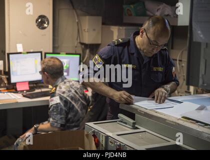 PEARL Harbor, Hawaii (16. Juli 2018) der chilenischen Marine Senior Chief Petty Officer Jose Mendez, um kombinierte Aufgabe Gruppe 176, Bewertungen von Dokumenten nach einer Schlacht briefing Update im Joint Operations Center der Amphibisches Schiff USS BONHOMME RICHARD (LHD6) während der Rand der Pazifischen (Rimpac) 2018 Übung. 25 Nationen, 46 Schiffe, 5 U-Boote, über 200 Flugzeuge und 25.000 Angestellte beteiligen sich an Rimpac vom 27. Juni bis 2. August in und um die hawaiischen Inseln und Südkalifornien. Die weltweit größte internationale maritime Übung RIMPAC bietet eine uniqu Stockfoto