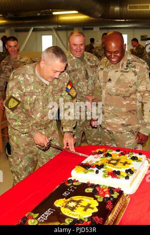 Us-Armee Oberstleutnant Kelvin Swint, rechts, Kommandant der 2. Battalion, 5th Cavalry Regiment, 1st Armored Brigade Combat Team, 1.Kavallerie Division Uhren auf Als rumänische Brig. Gen. Dragoș Iacob, J7 - Leiter der Ausbildung und Lehre Direktion, schneidet ein zeremonielles Kuchen folgenden uncasing Zeremonie des Bataillons in Mihail Kogalniceanu, Rumänien, 17. Juli 2019. Die uncasing Zeremonie offiziell den Start der 2-5 CAV's Mission in Rumänien und setzt die Partnerschaft zwischen der US- und NATO-Partnern und Verbündeten zu stärken. Stockfoto