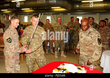 Us-Armee Oberstleutnant Kelvin Swint, rechts, Kommandant der 2. Battalion, 5th Cavalry Regiment, 1st Armored Brigade Combat Team, 1.Kavallerie Division, Uhren auf die U.S. Army Command Sgt. Maj. Aron Eingetragen von Alexander, Senior Advisor für die 2-5 CAV, 1 ABCT, 1 CD und rumänischen Command Sgt. Maj. Valentin Stanciu, command Sgt. Maj. Für 284. Gepanzertes Bataillon, schneidet die zeremoniellen Kuchen während eines Mittagessens nach uncasing Zeremonie des Bataillons in Mihail Kogalniceanu, Rumänien, 17. Juli 2018 statt. Die uncasing Zeremonie offiziell markiert den Beginn der 2-5 CAV's Mission in Rumänien und fortfahren Stockfoto