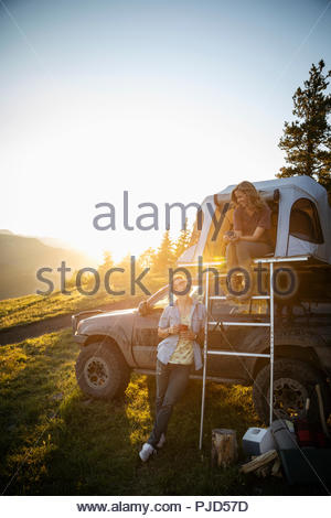 Paar camping, entspannen im SUV Dachzelt in sonniger, idyllischer Feld, Alberta, Kanada