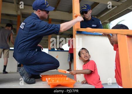 Besatzungsmitglieder aus der U.S. Coast Guard Cutter Oliver Berry (WPC 1124) ein Park mit einheimischen Kindern auf Majuro Atoll, 5. Juli 2018 malen. In einer Bemühung, Coast Guard Präsenz, Bewusstsein und Beziehungen zu verbessern, die Besatzungsmitglieder freiwillig helfen Teile des Parks neu lackieren und Abfall reinigen. Stockfoto