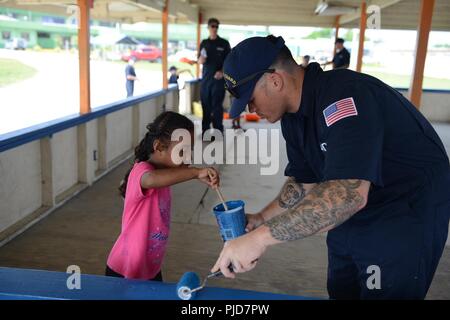 Besatzungsmitglieder aus der U.S. Coast Guard Cutter Oliver Berry (WPC 1124) ein Park mit einheimischen Kindern auf Majuro Atoll, 5. Juli 2018 malen. In einer Bemühung, Coast Guard Präsenz, Bewusstsein und Beziehungen zu verbessern, die Besatzungsmitglieder freiwillig helfen Teile des Parks neu lackieren und Abfall reinigen. Stockfoto