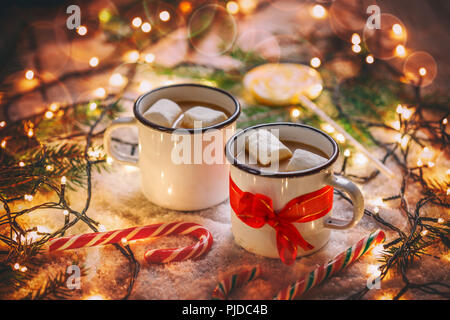Zwei Portionen heiße Schokolade mit Marshmallows in Emaille Becher mit roter Schleife gebunden Stockfoto