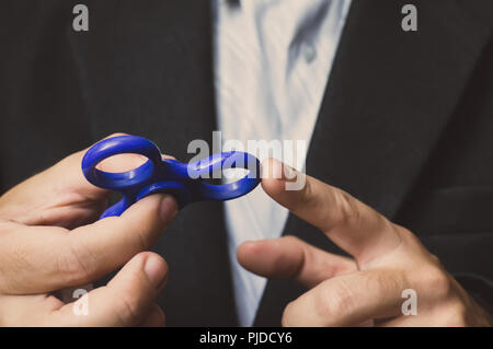 Ein Mann hand Halten einer Hand grüne Spinner oder zappeln Spinner auf dem Hintergrund. Leistungsstarke Spinner, Twister für Hände Unterhaltung rotierende Spielzeug. Antistres Stockfoto