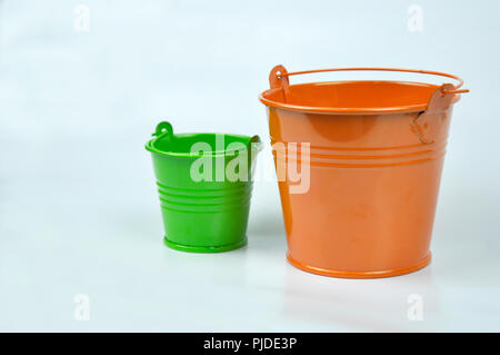 Kleine orange und grüne Eimer auf weißem Hintergrund. Stockfoto