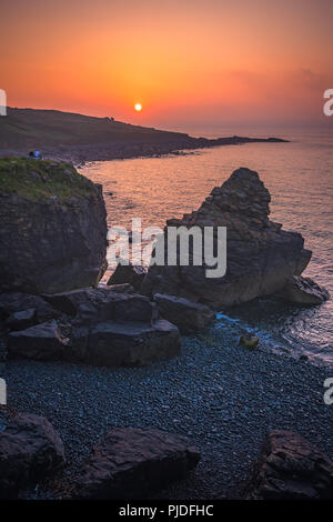 St. Ives, England - Mai 2018: Paar auf einem Stein saß und bewundern Sie den Sonnenuntergang über der Cornwall, Cornwall Stockfoto