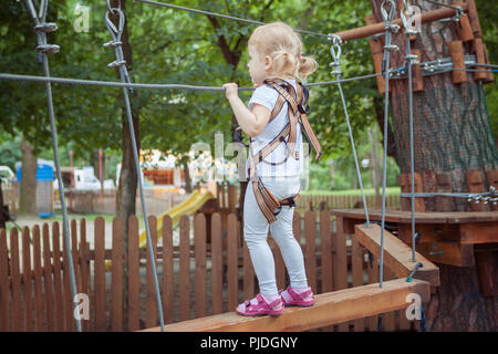 Kleine brave Mädchen auf der Suche nach Abenteuer überwindet das Hindernis in den Seilpark. Stockfoto