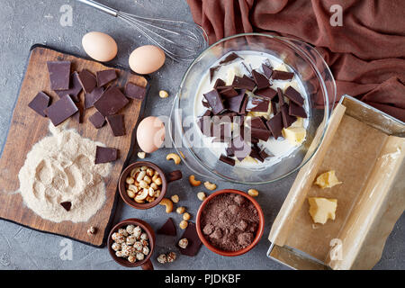 Die leckere Schokolade Gebäck aus Buchweizen Mehl, Eier, dunkle Schokolade, Nüsse, Milch und Butter. Zutaten, Schneebesen, Metall Backform auf einem concre Stockfoto