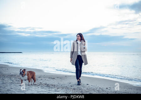 Junge Frau am Strand entlang zu laufen mit Hund Stockfoto