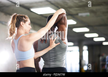 Trainer helfen Menschen mit Stretching Training im Fitnessraum Stockfoto