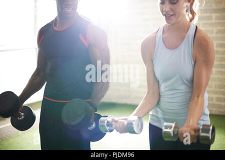 Trainer und weibliche client Hanteln in der Turnhalle Stockfoto