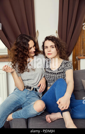 Zwei junge weibliche Freunde sitzen auf einem Sofa portrait Stockfoto