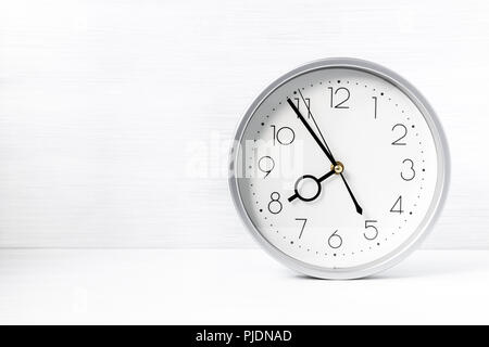 Wanduhr Silber auf Weiß Holzschreibtisch. Kopieren - Raum. Stockfoto