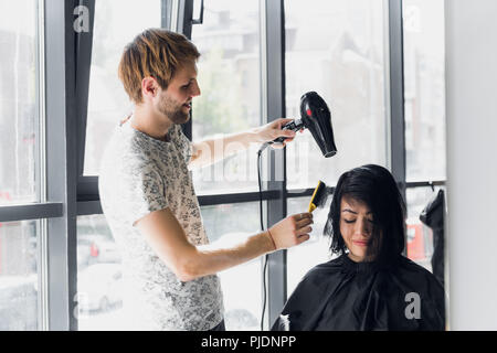 Junge Frau, ihr Haar in Haar Salon durch ein stattliches Friseur hairstylist gekleidet