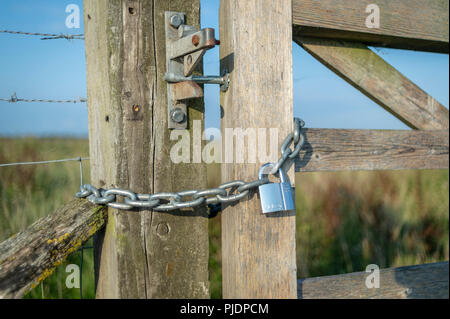 Vorhängeschloss und Kette auf einer hölzernen farm Gate, aus der Nähe. Stockfoto