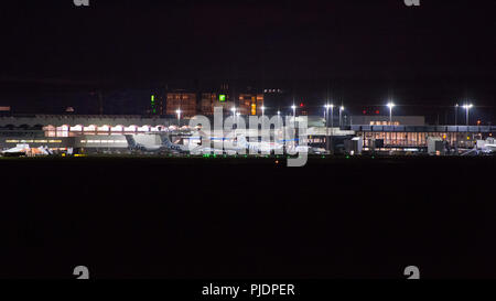 Niedrige Kosten Betreiber Flybe die Bombardier Q400 Flugzeuge benutzen, bei Nacht gesehen, der Internationale Flughafen Glasgow, Renfrewshire, Schottland. Stockfoto