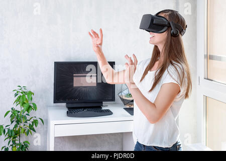 Lächelnd positive Frau mit Virtual reality Brillen Headset, VR-Box. Verbindung, Technologie, neue Generation, Fortschritt Konzept. Mädchen versuchen zu berühren Stockfoto