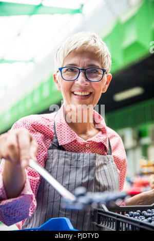 Portrait der älteren Frau verkauft Himbeeren auf dem Markt Stockfoto