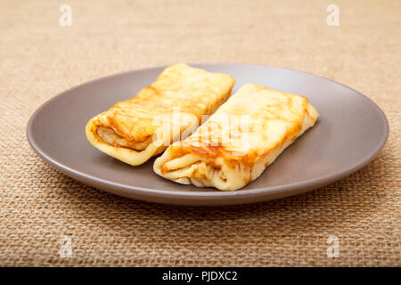 Hausgemachte Pfannkuchen mit Hüttenkäse auf dem Teller gefüllt mit Sack auf Hintergrund Stockfoto