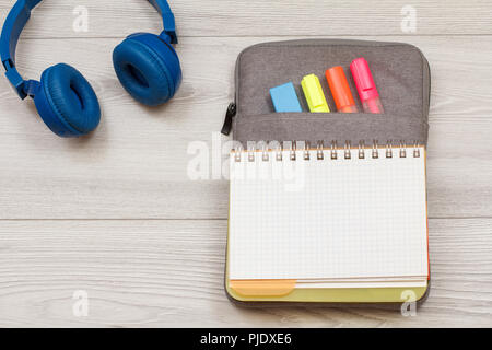 Die Schule liefert. Kopfhörer, Öffnen Sie dazu die Übung Buch auf Tasche - Federmäppchen mit Farbe filzstifte und Marker auf grau Holzbretter. Ansicht von oben mit der Kopie. Ba Stockfoto