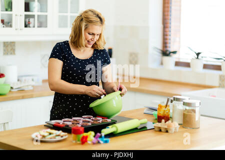 Schöne schwangere Frau Vorbereitung Muffins Stockfoto