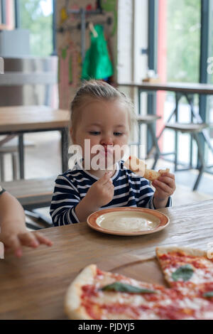 Süße kleine lustige 2 Jahre Mädchen essen Pizza im Restaurant Stockfoto